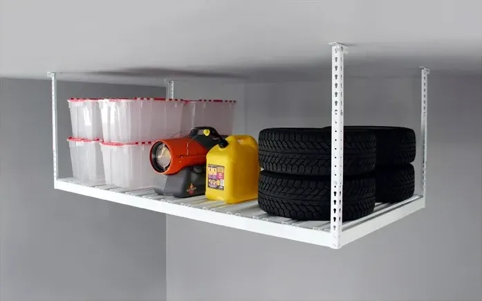 White ceiling-mounted overhead storage rack holding totes, tires and a gas can.