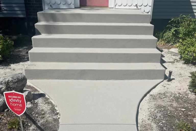 Freshly poured concrete stairway leading up to a landscaped entry.