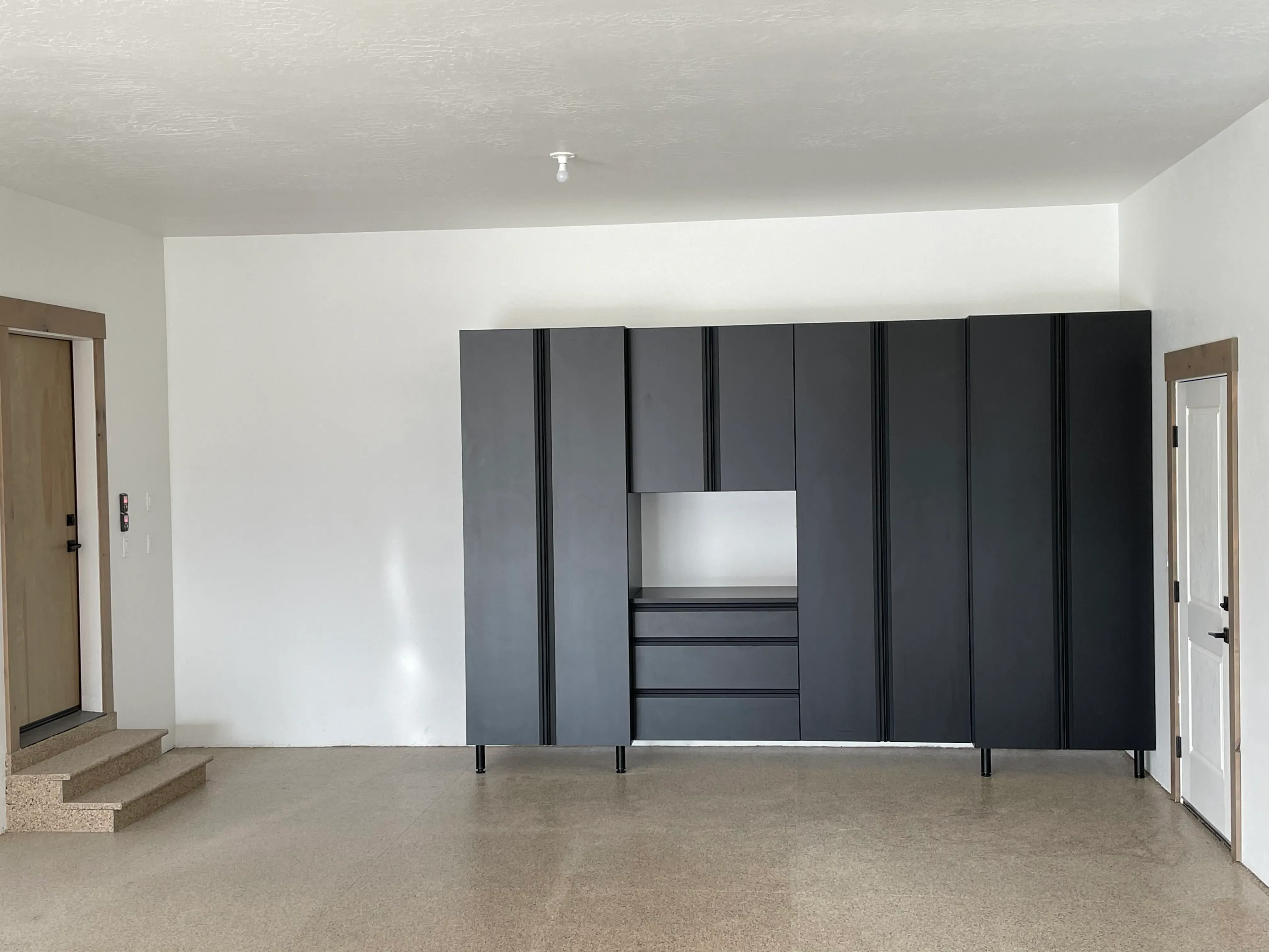 Black garage storage cabinets with black channel pulls against a coated floor.