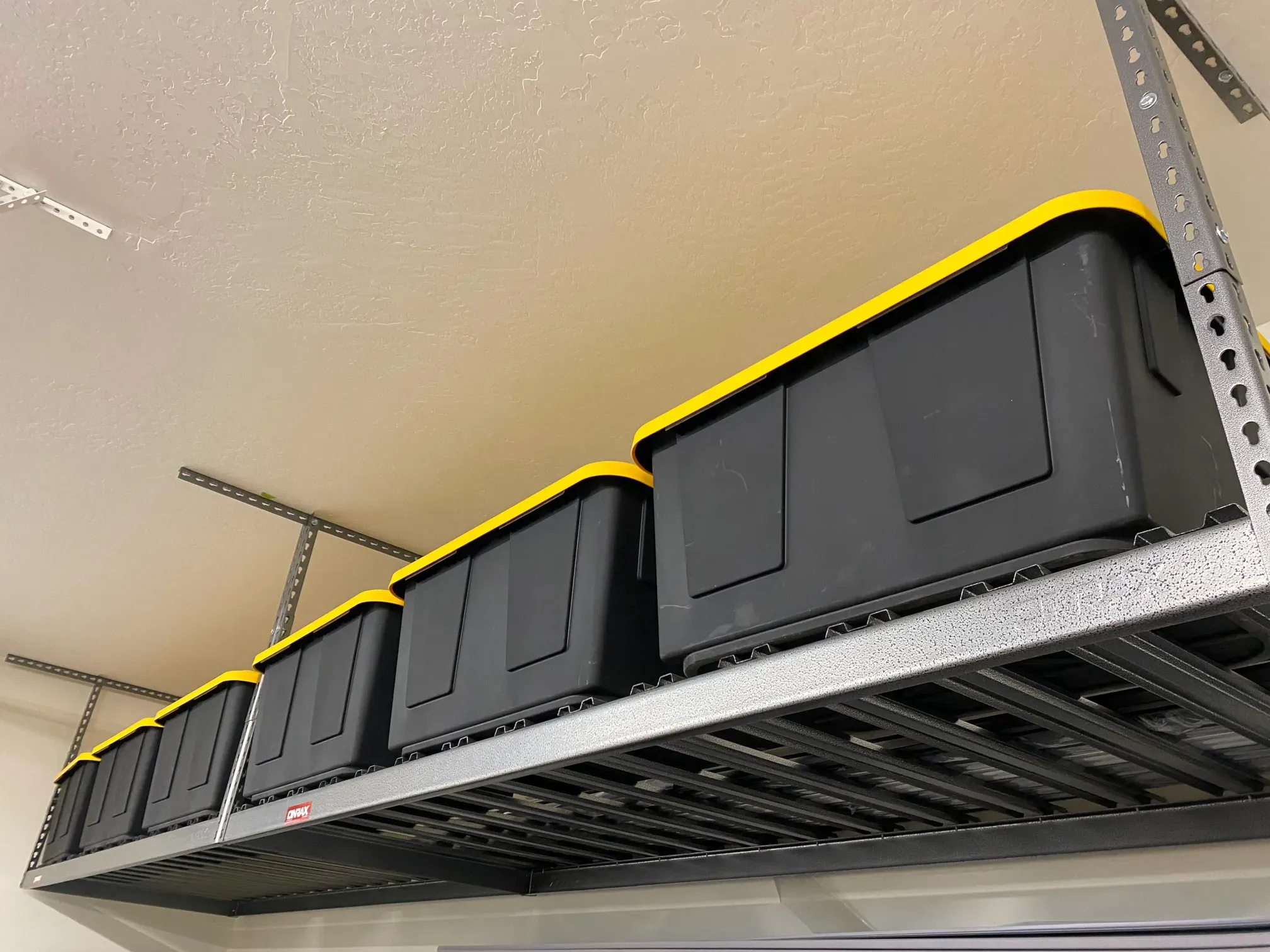 Overhead storage rack loaded with black and yellow storage bins.