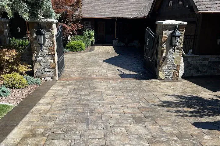 Sealed stamped-concrete driveway between stone entry columns.