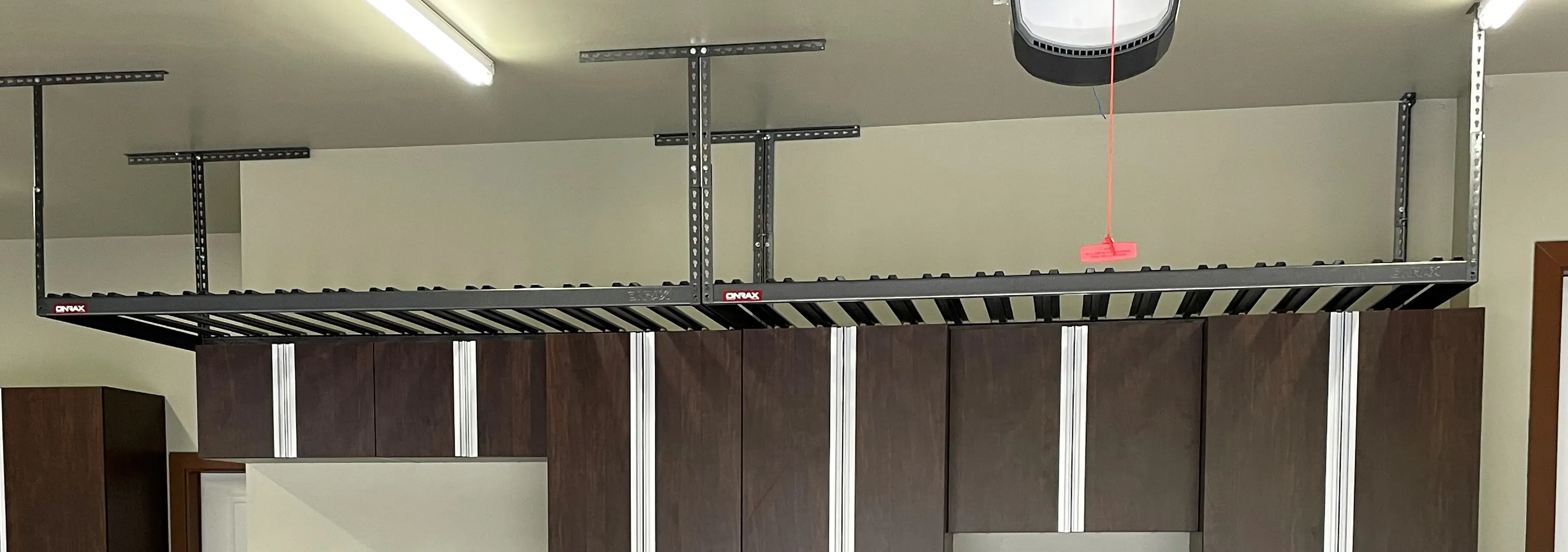 Long run of overhead garage storage racks mounted above dark cabinets.
