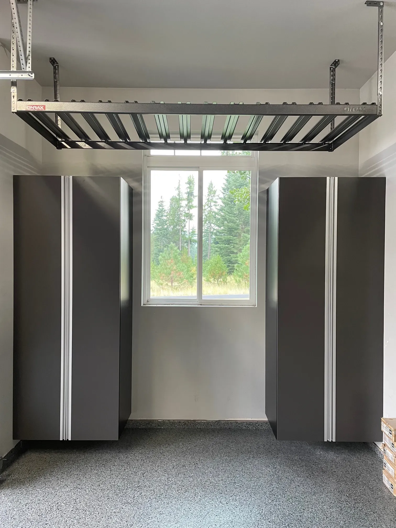Empty overhead storage rack mounted to a garage ceiling above gray cabinets.