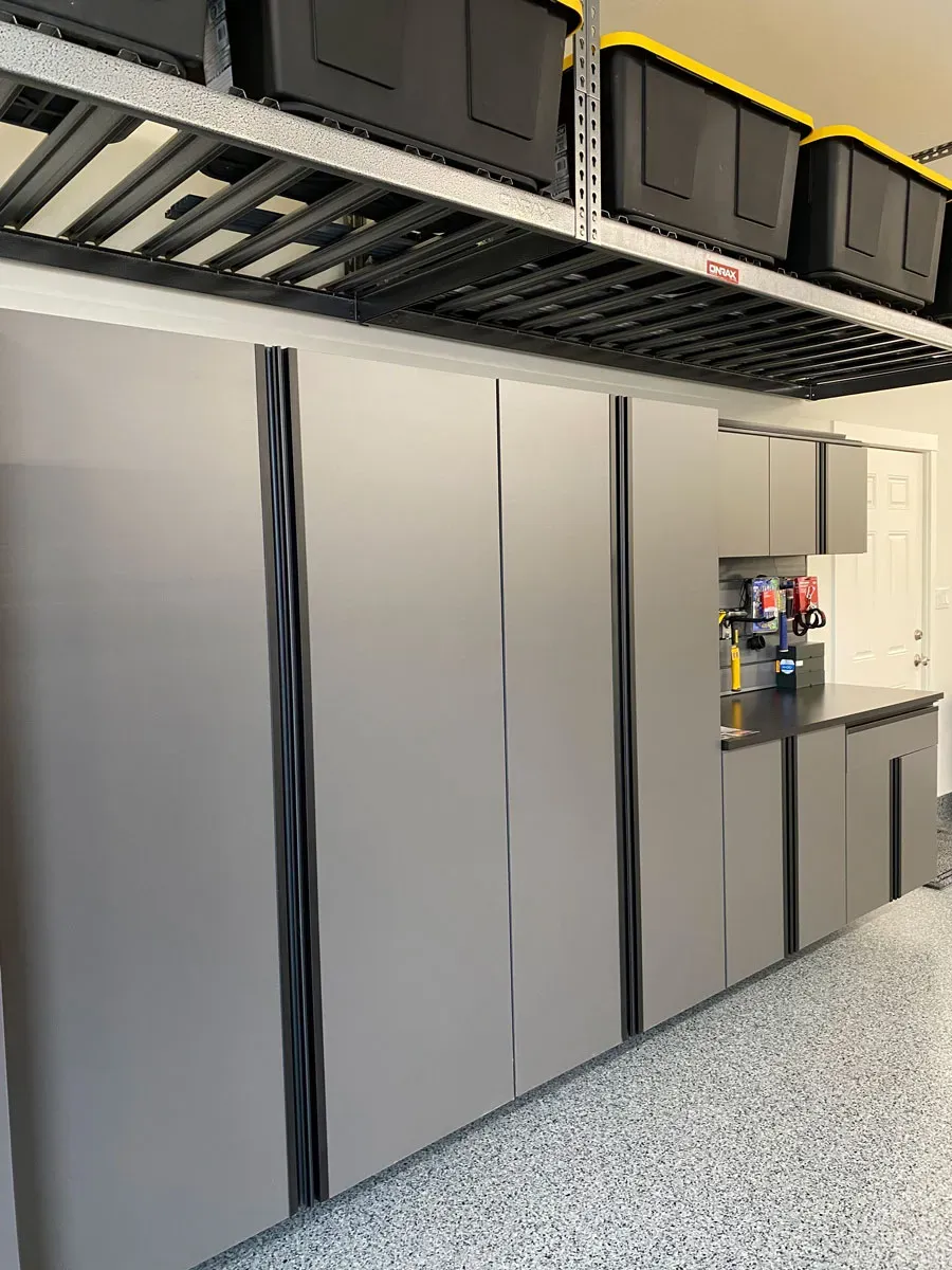 Garage storage cabinets and an overhead rack installed above a speckled epoxy floor.